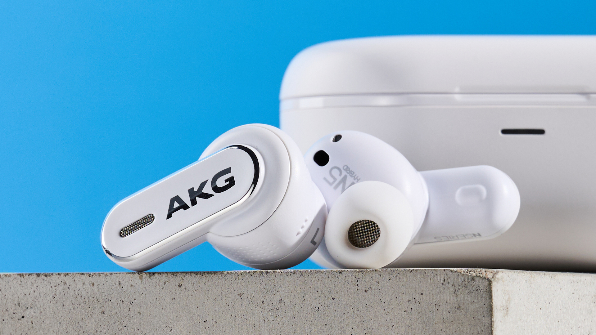 the akg n5 hybrid earbuds by harman in white, shown in their charging case with accessories and without