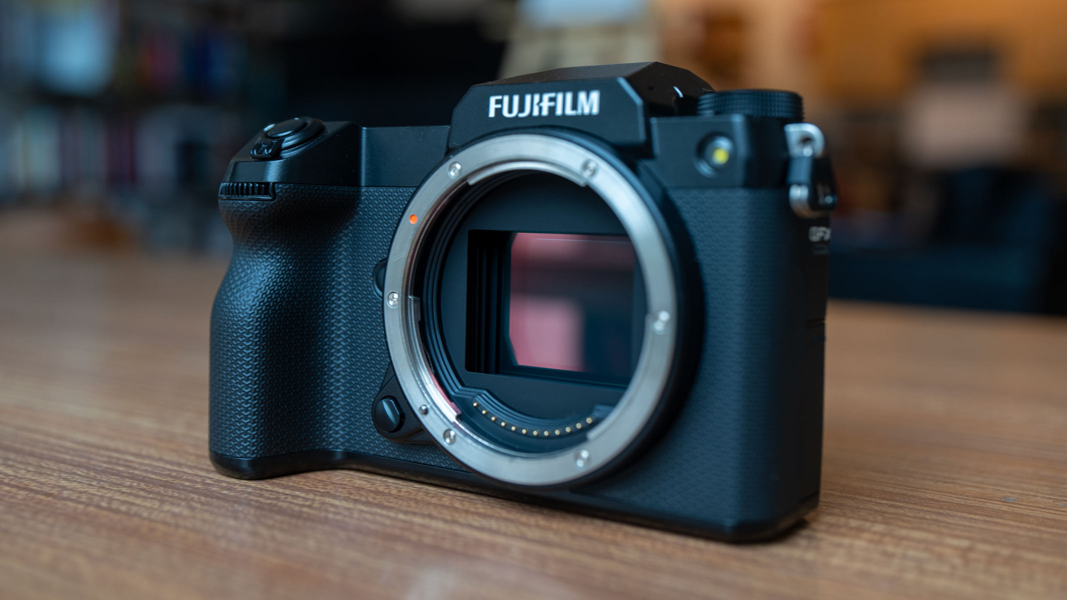 A side-on view of the Fujifilm GFX100S II, on a wooden table.