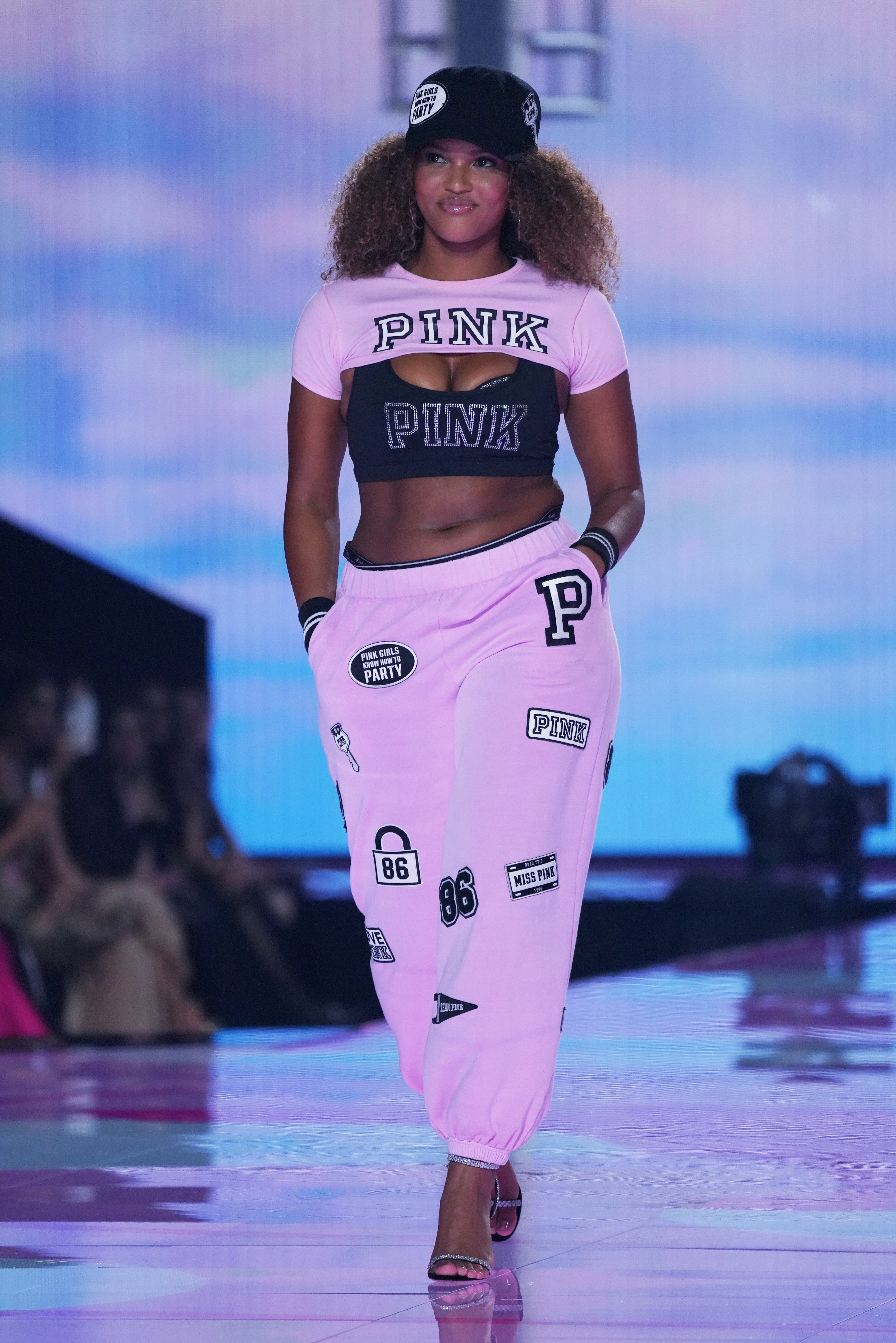 a model on the Victoria&#039;s Secret Fashion Show runway wearing a pink t shirt and sweatpants