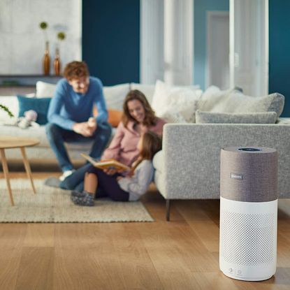 Family sat in a living room with the Philips AC3033/30 air purifier on display