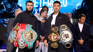 Artur Beterbiev and Dmitry Bivol stand together with their light-heavyweight championship belts.