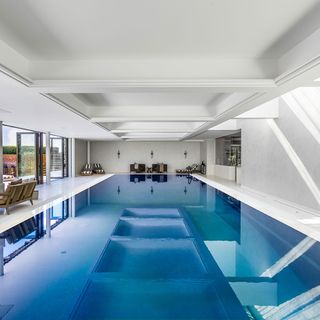 swimming pool with sunloungers and white wall