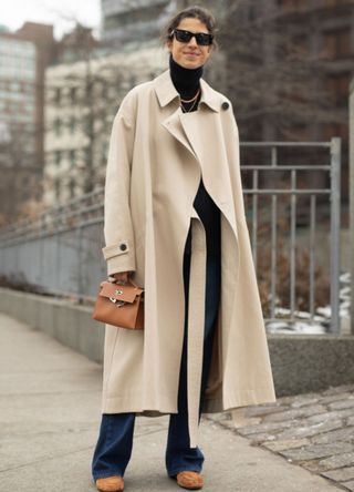 Leandra Medine in a long trench coat with flared jeans.