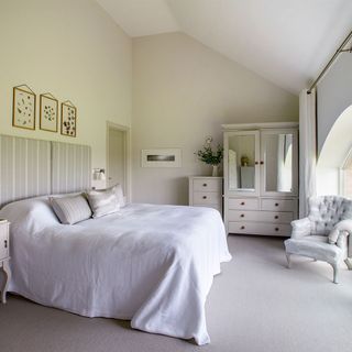 bedroom with white wall white bed white cupboard and chair