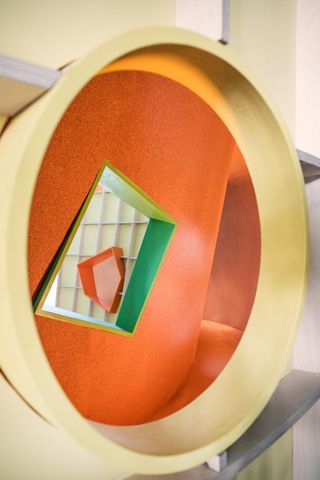 Looking through a circular window to the orange interior of a playhouse.
