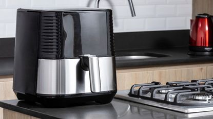 A black and silver air fryer on a kitchen side