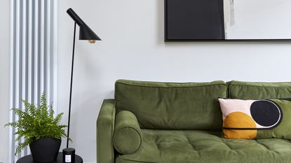 Living room with pink and red accents and gold standing lamp./