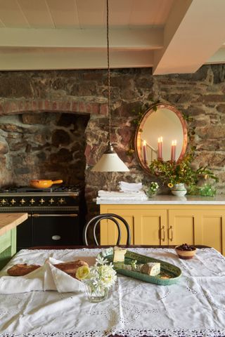Traditional English kitchen with stone wall and agar, yellow cabinet