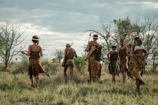 Indigenous San people walk through the landscape in Botswana, Africa.