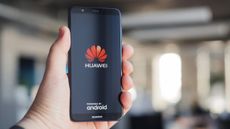 A Huawei handset held in an outstretched hand displaying the Huawei and Android logos on-screen