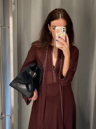 Woman wears burgundy dress and black tote bag