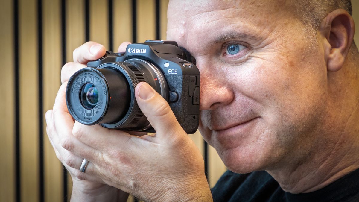 Peter Travers holding the Canon EOS R100 camera