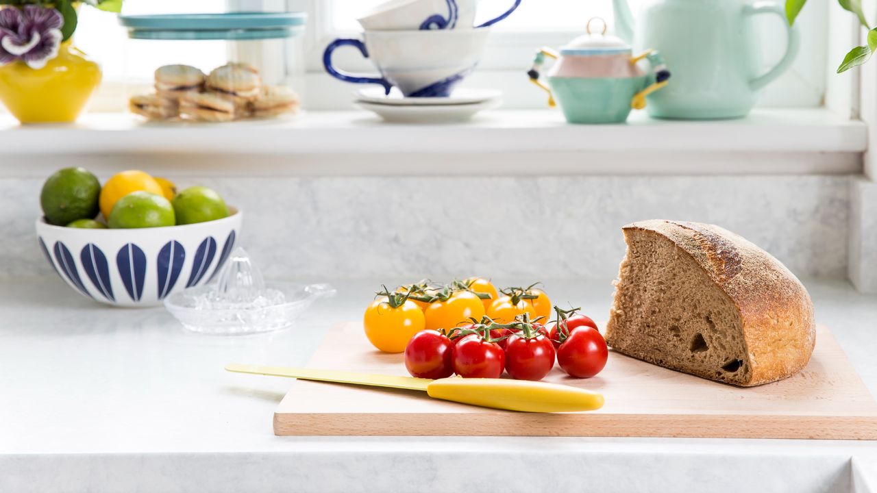 A kitchen worktop with a bread and cherry tomatoes on a cutting board