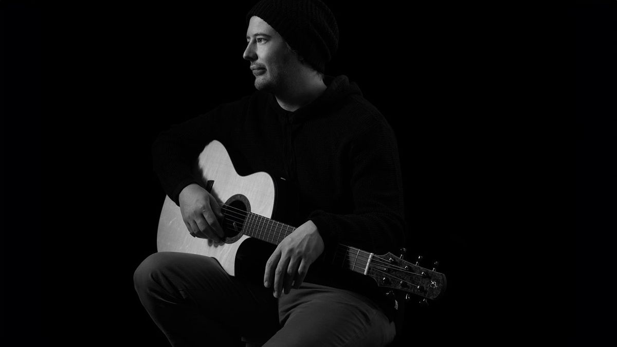 Alan Gogoll poses with an acoustic guitar