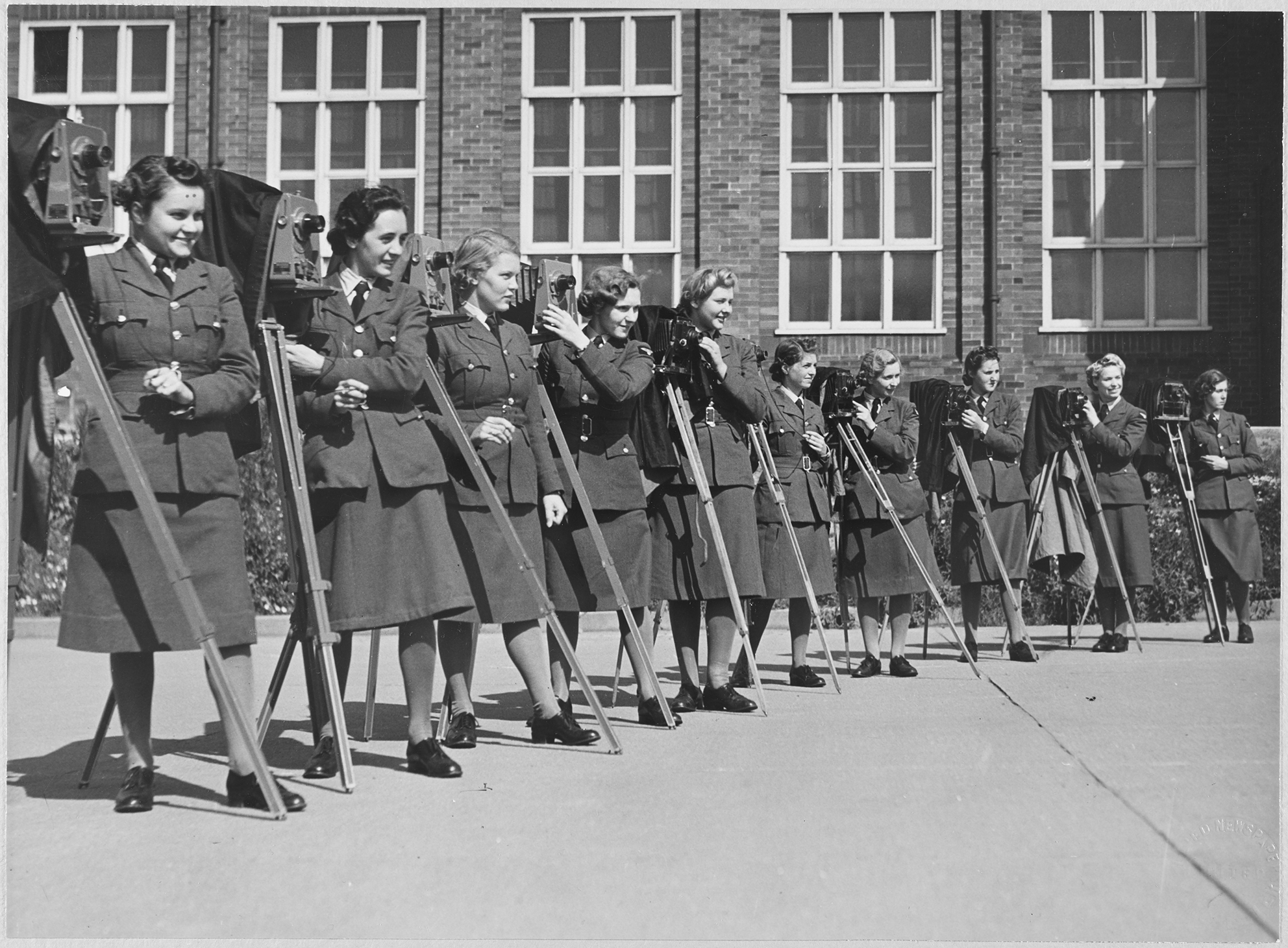 A group of women from the Women's Auxiliary Air Force, in military uniform, posed with their cameras outside the RAF's No. 2 School of Photography