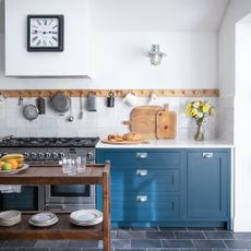 Blue kitchen with wooden peg rail, black slate floor tiles