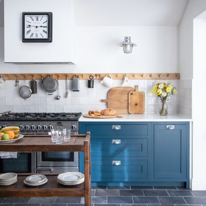 Blue kitchen with wooden peg rail, black slate floor tiles