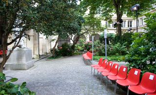 Red chairs aligned under the garden's portico