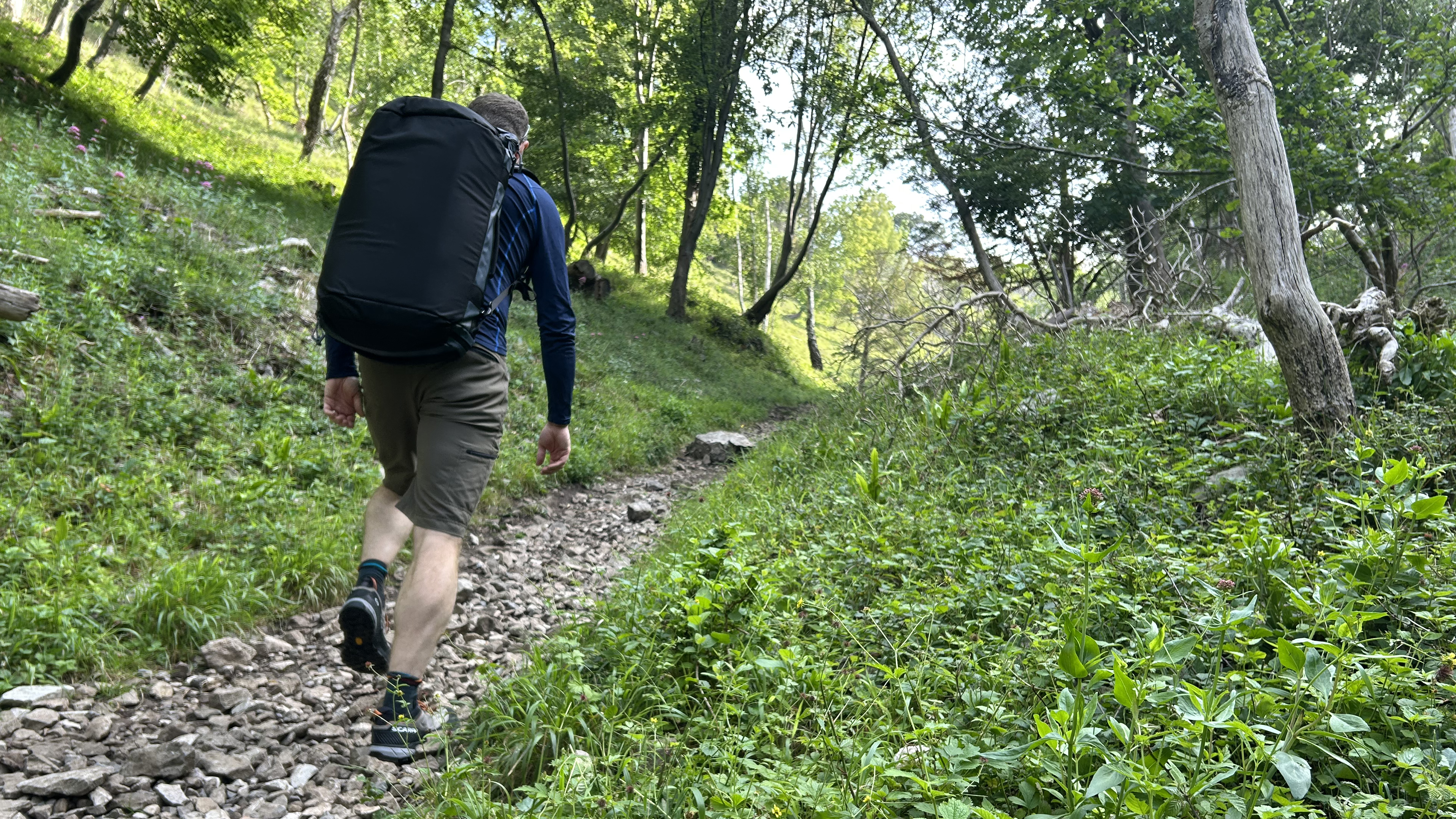 A hiker shouldering the Wandrd Carryall Duffel