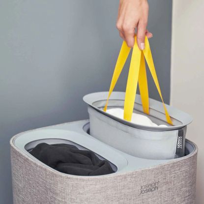 Pulling out one compartment of the Joseph Joseph laundry basket in grey