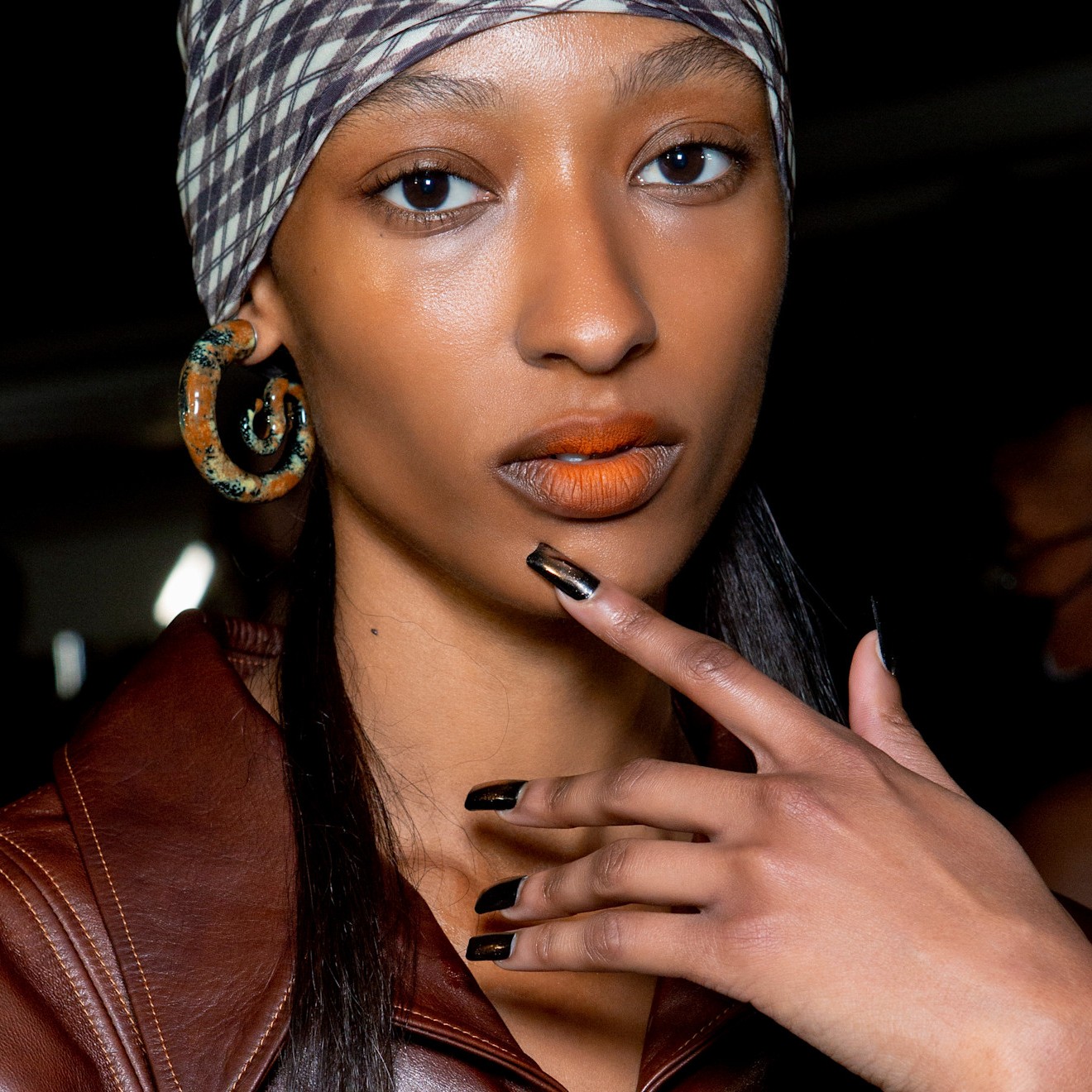 woman with a brown manicure and orange lipstick