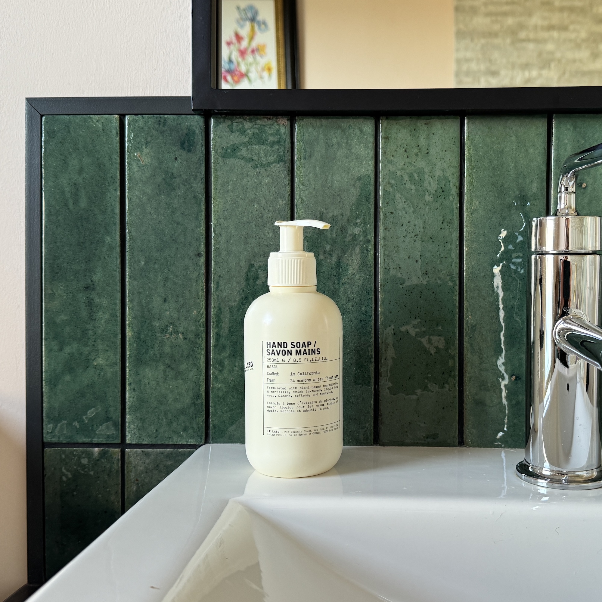 green tiles with black grout and white basin/chrome tap