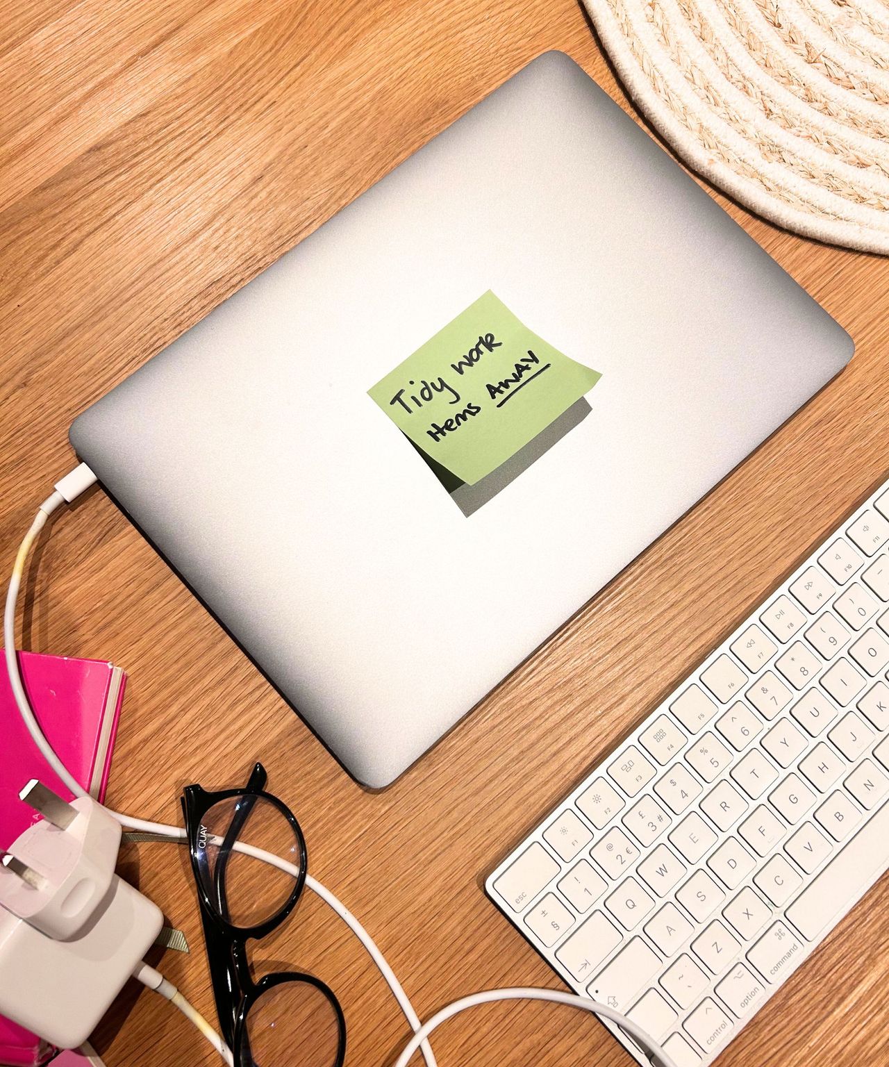 After using the visual clues trick: wooden table with laptop and keyboard on it with green Post-it note on laptop.