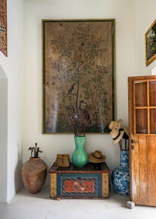 entryway with front door open and colored chest walking sticks and hats in blue jar and big silk embroidery picture