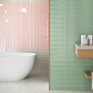 a bathroom with one wall made up of pastel green wall tiles laid horizontally, another wall made up of mostly pink wall tiles laid veritcally with grey wall tiles laid horizontally underneath, and a freestanding white bathtub in front of the wall