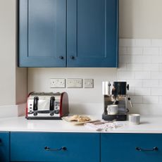 A blue kitchen with a toaster and a coffee machine