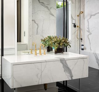 marble bathroom with marble wall hung vanity, large mirror, dark grey floor tiles