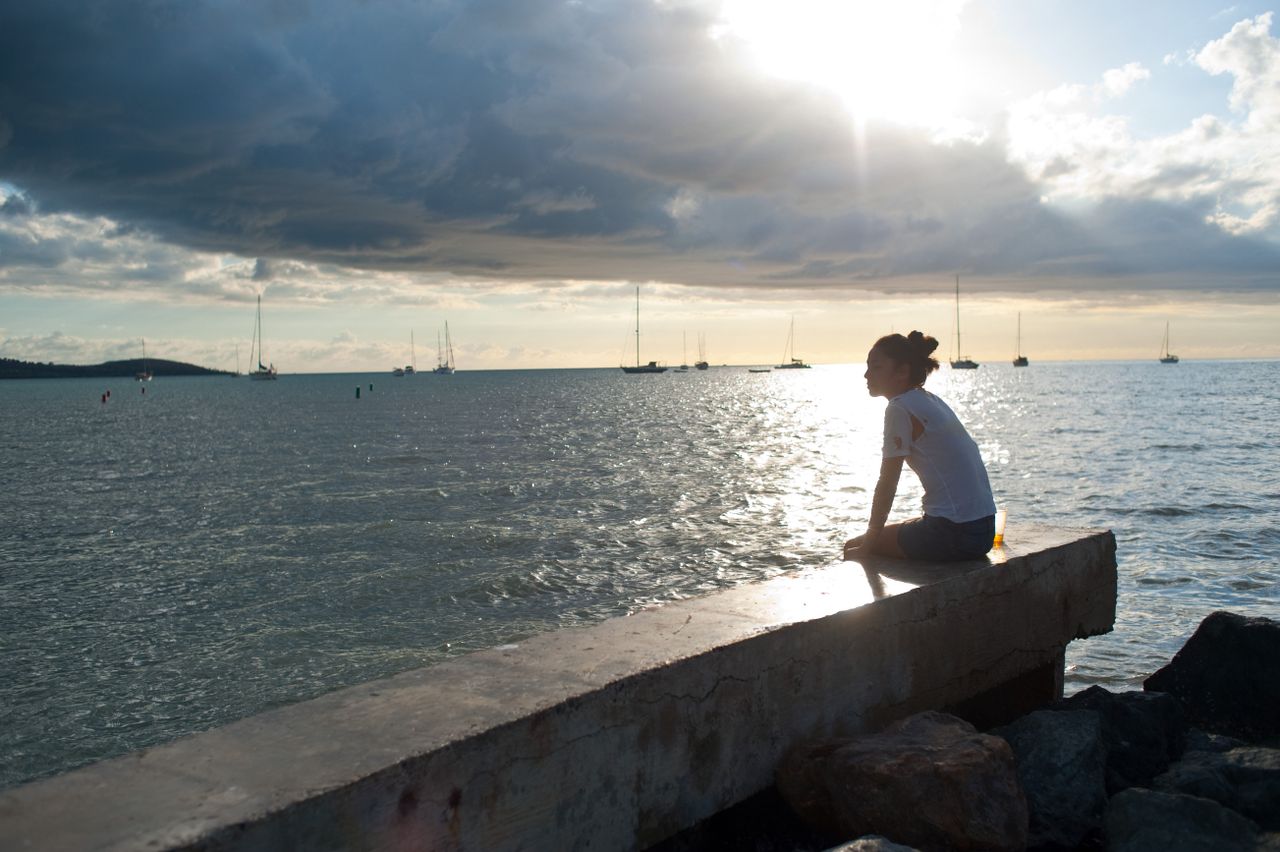 A woman sitting by the ocean.