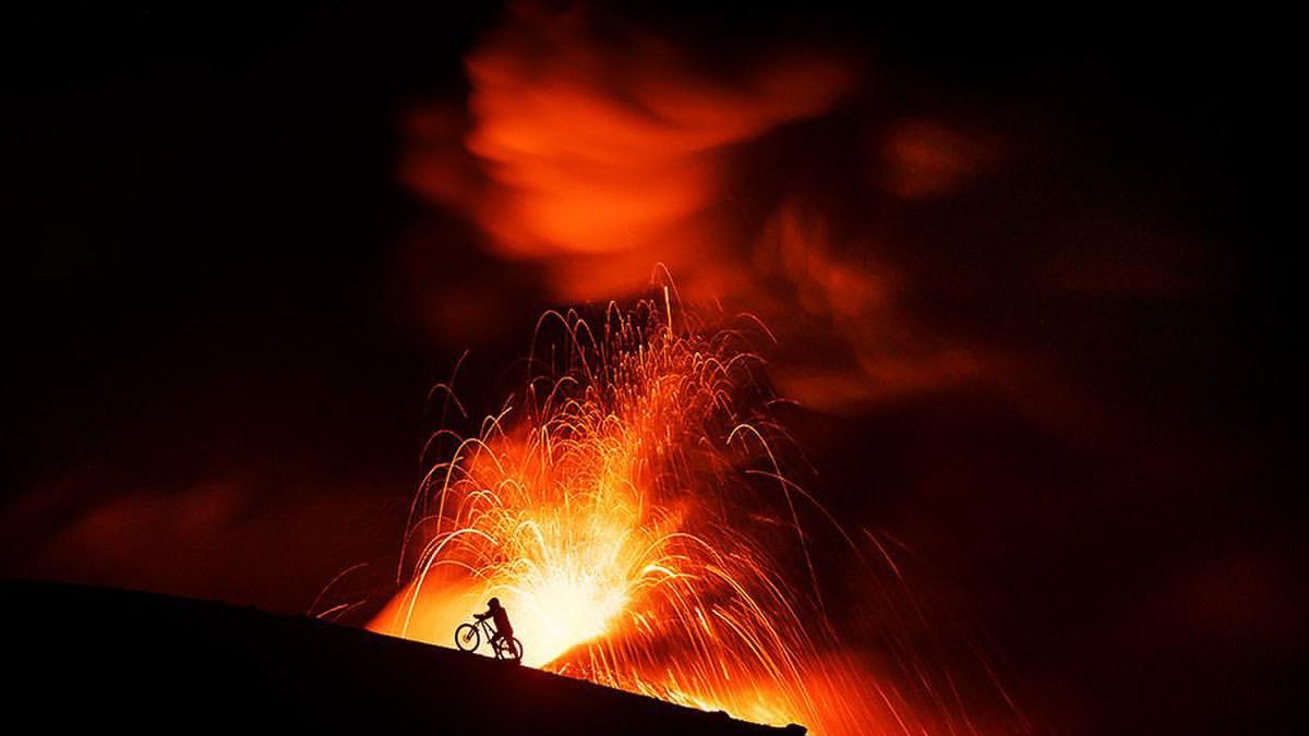 Kilian Bron pushing his mountain bike up an active volcano