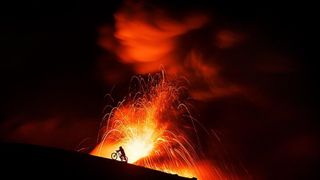 Kilian Bron pushing his mountain bike up an active volcano