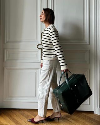 French woman wearing a striped jacket and cream-colored jeans.