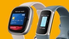 A Fitbit smartwatch and fitness tracker on an orange background