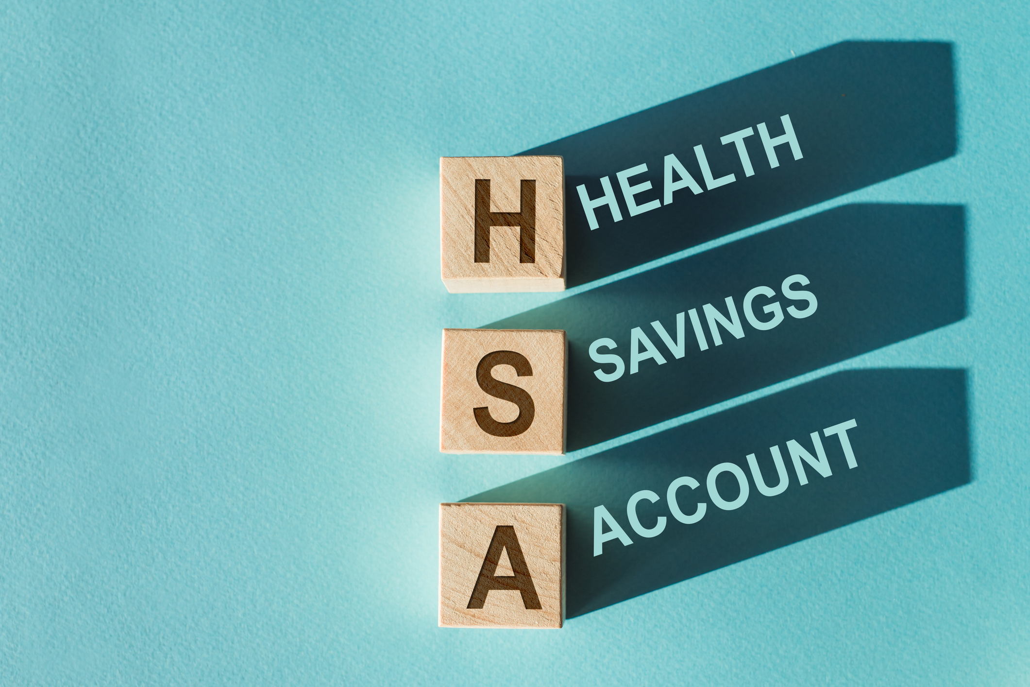 wooden letters spelling "Health Savings Account" on bright blue background