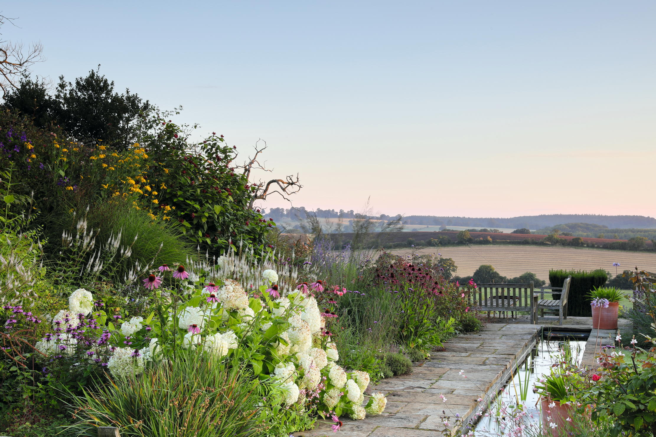 A formal rill leads to the seating area and the wonderful view, with Hydrangea arborescens Annabelle. The garden of the Old Rectory at Preston Capes, Northamptonshire. Photographs by Britt Willoughby Dyer for Country Life.