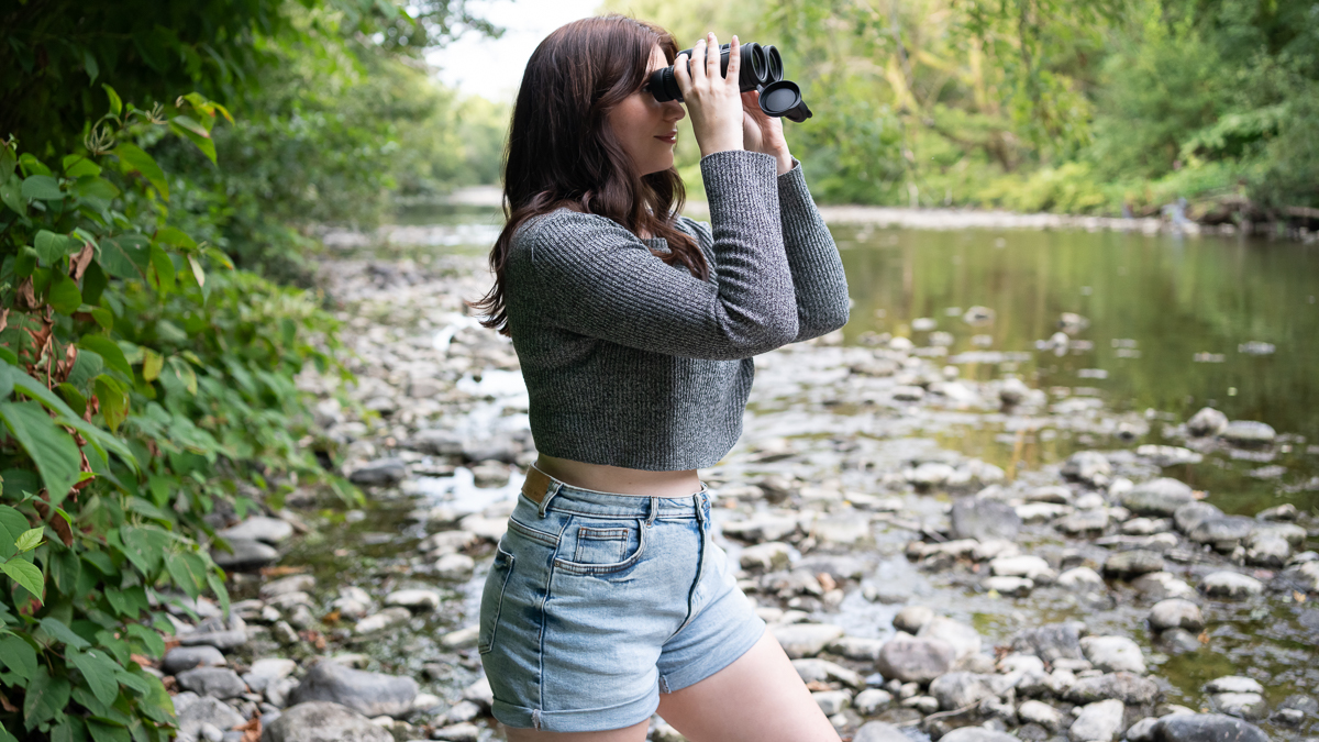 woman using the Celestron TrailSeeker 10x42 by a river
