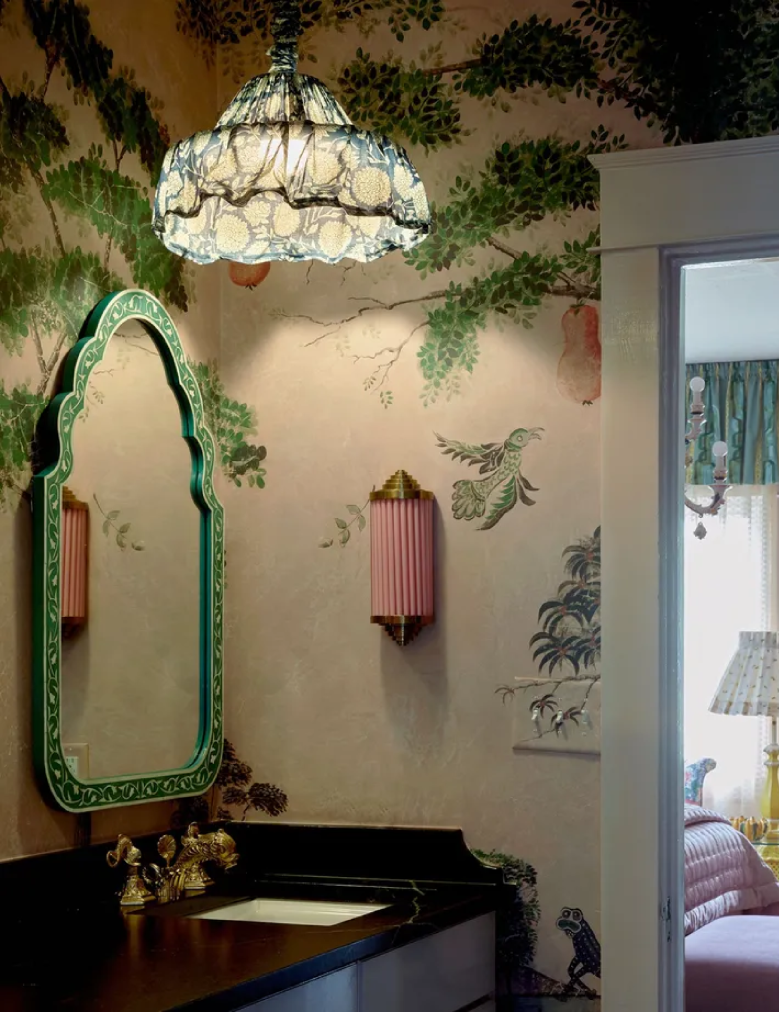 Vintage style bathroom with green mirror and pink wallpaper and botanical mural