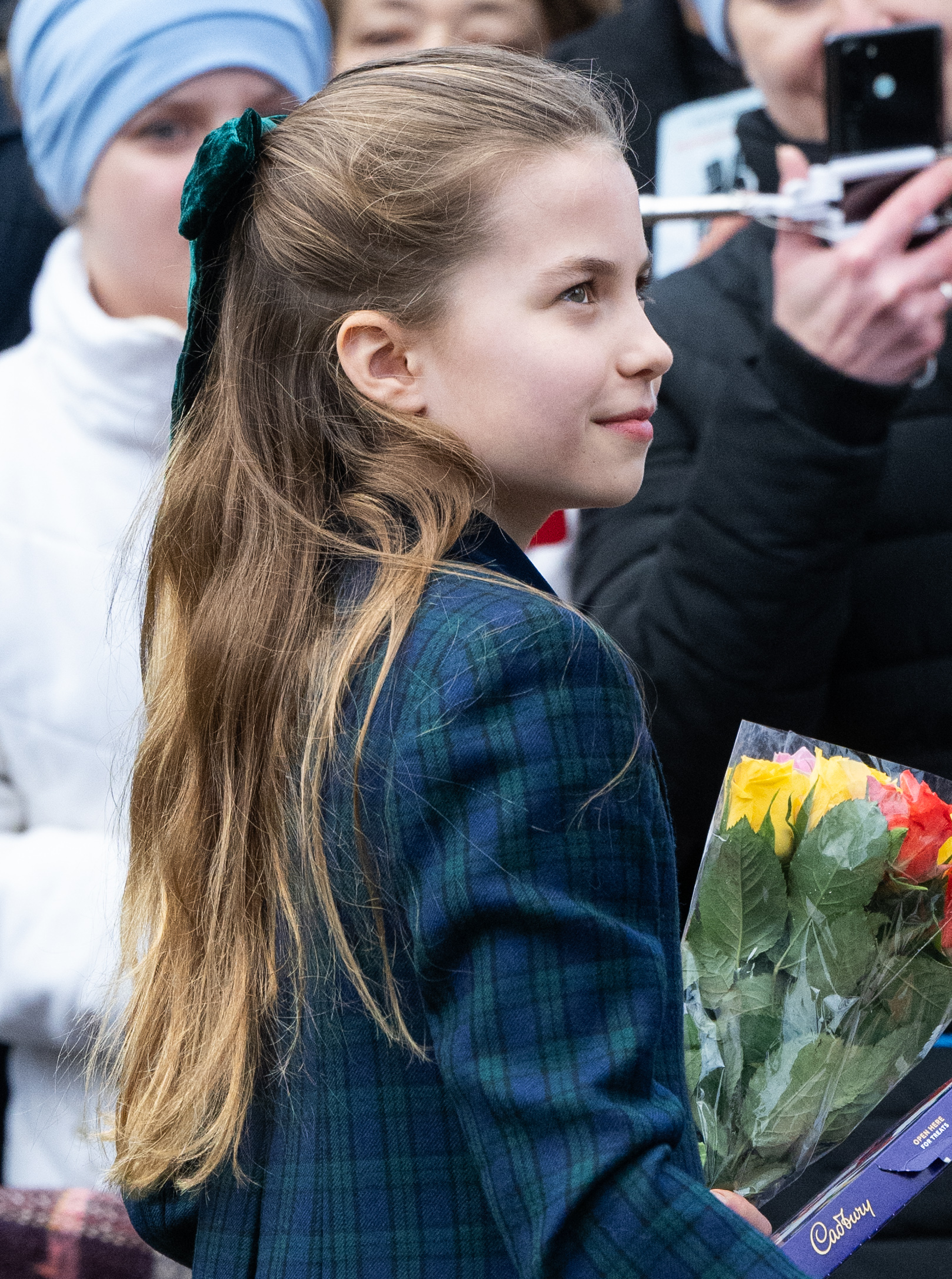 Princess Charlotte wearing a plaid coat holding flowers on Christmas Day 2024