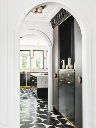 small home bar in alcove near kitchen, monochromatic with brass fixtures and fittings, black and white tiled floor