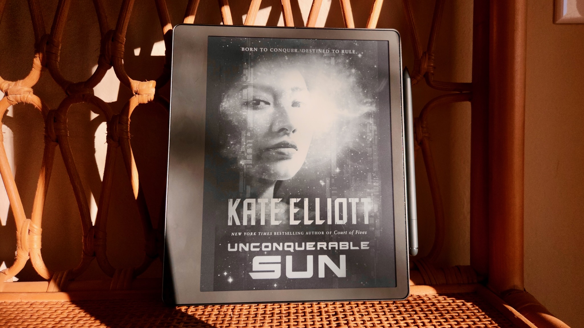 A close-up of the Amazon Kindle Scribe showing an e-book cover for Unconquerable Sun by Kate Elliot