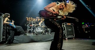 The Warning's Daniela and Ale Villarreal Velez onstage with a purple PRS guitar and blue bass respectively