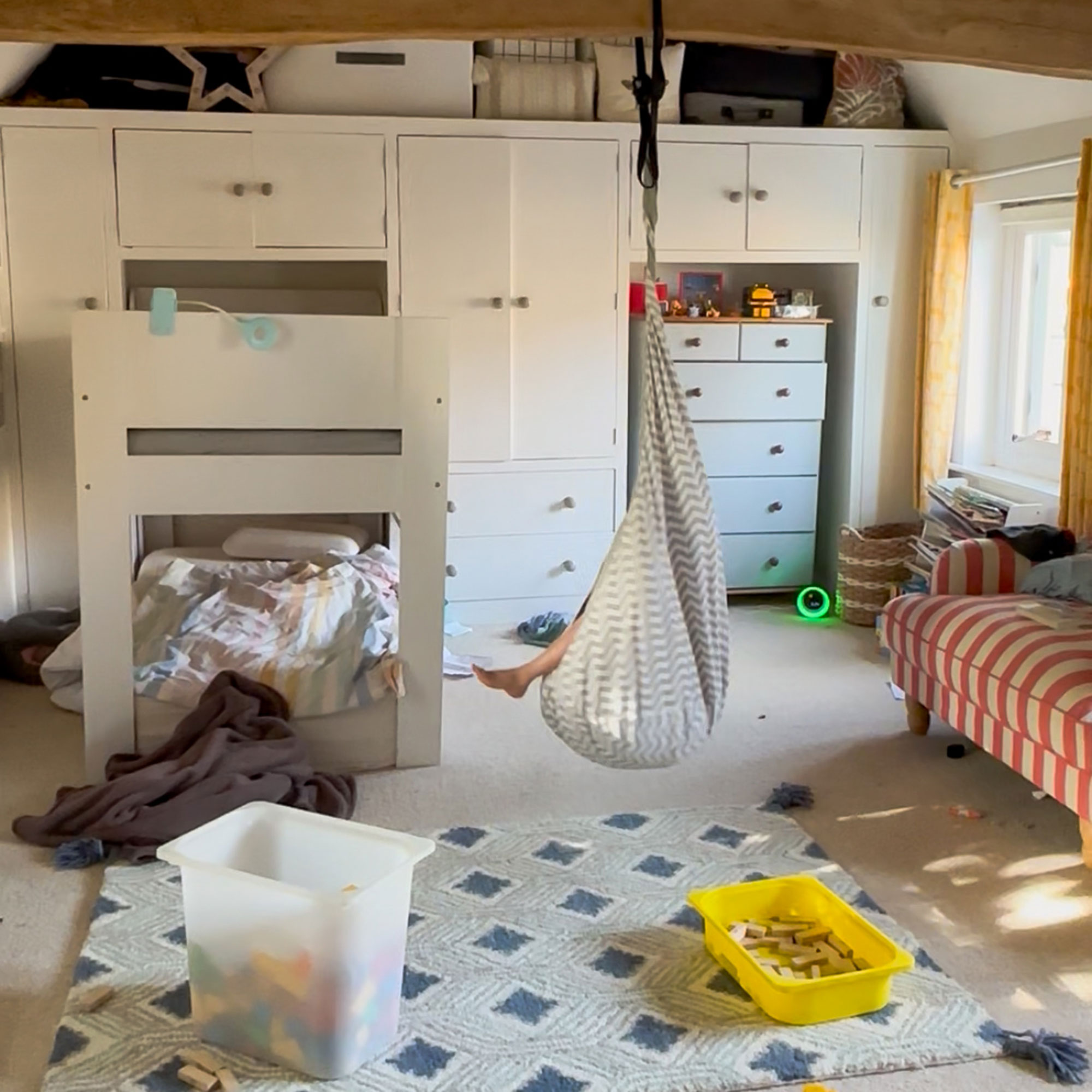 Kids room with child in swing seat hanging from wooden ceiling beams