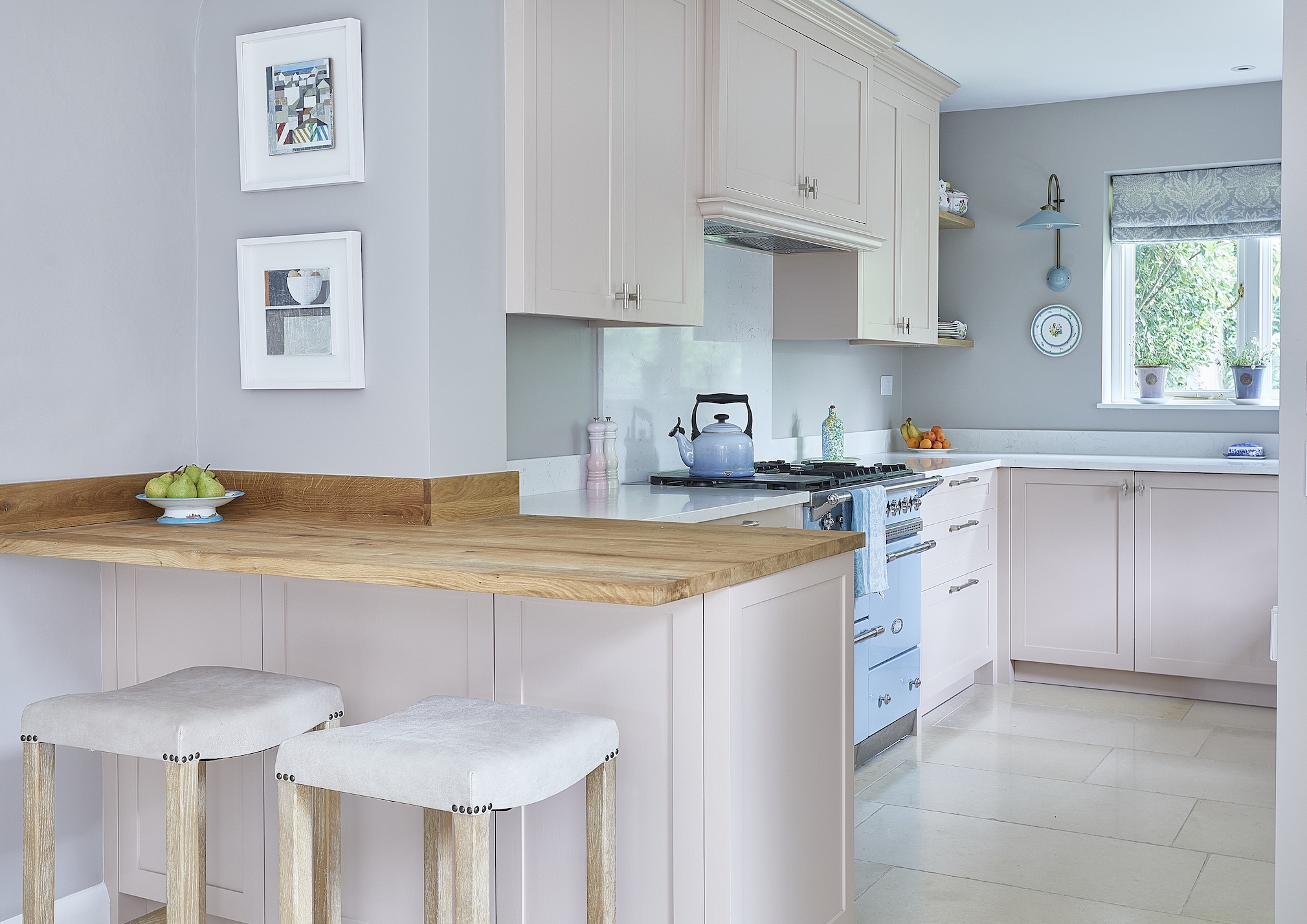 A pink kitchens with a breakfast bar built into the strictural pillar to make best use of space