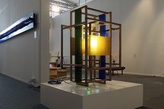 View of 'Ion' by Carolina Wilcke - a wooden, green and blue structure with a light in the centre on a small white plinth
