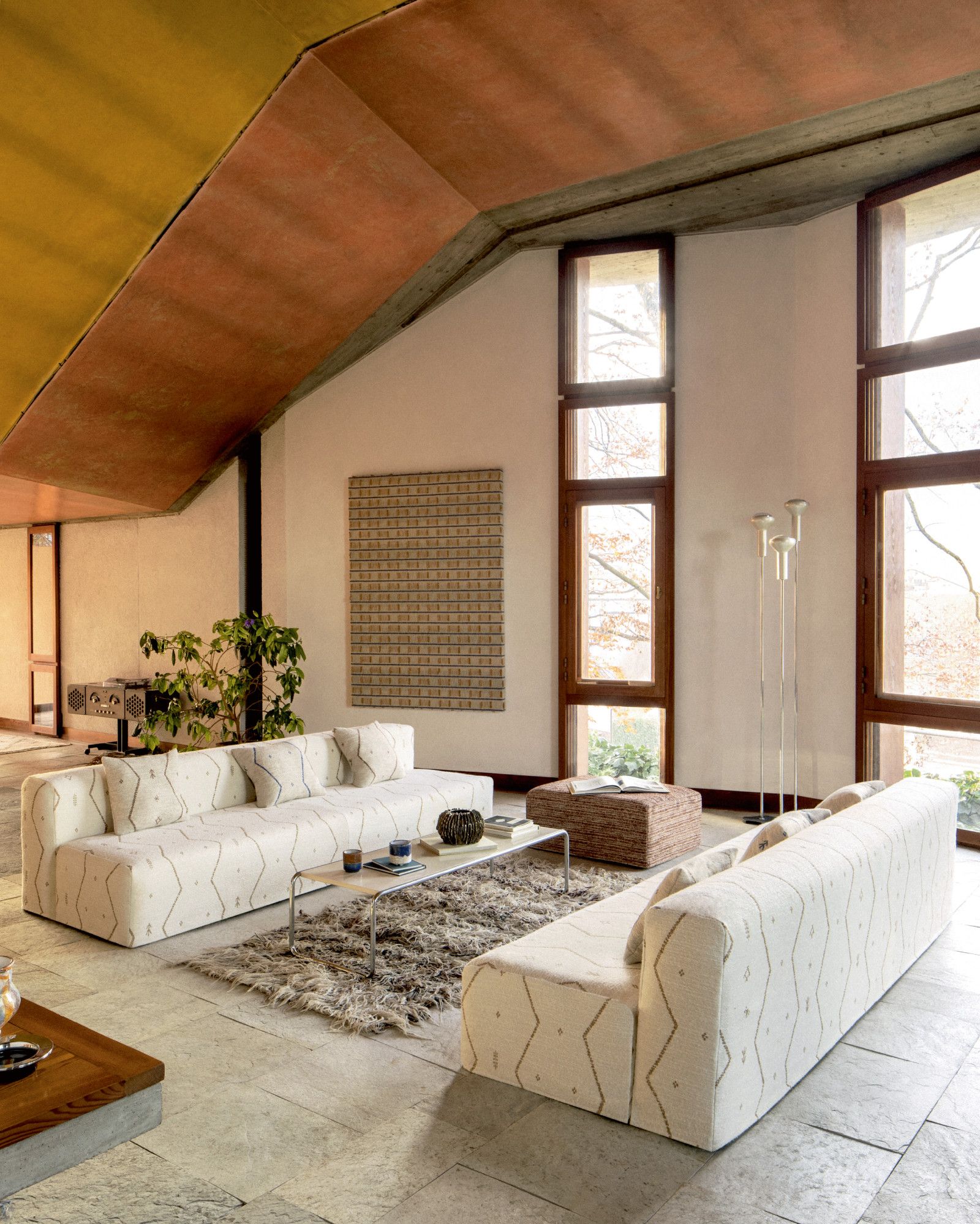 Living room with white walls, wood cladded ceiling and sofas in embroidered fabric