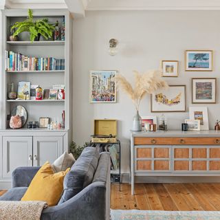 grey walled living room with sideboard and bookcase with display items, and prints on wall