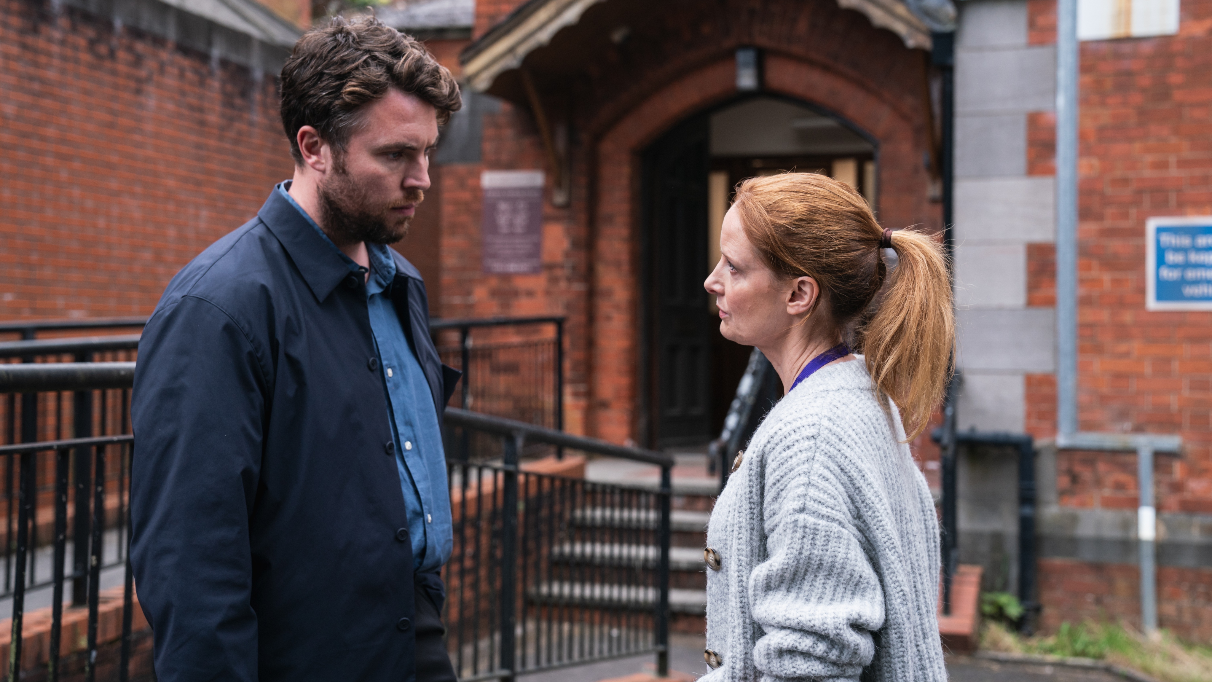 Pictured: TOM HUGHES as DR James Ford and ZOE TELFORD as DR Kate McALLISTER talking outside the hospital.